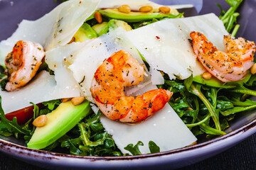 Fresh salad bowl with arugula, avocado, shrimps, parmesan cheese and pine nuts. Healthy food. Diet menu.