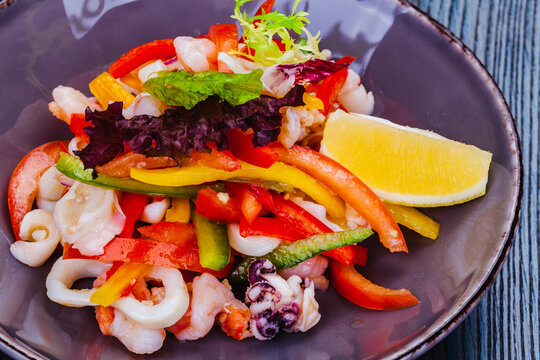 Salad with squid, bell pepper and onion on gray plate