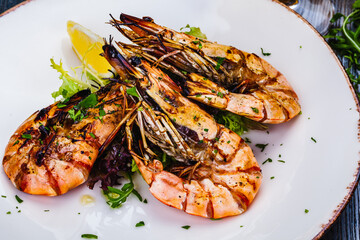 Grilled tiger prawns with greens on white plate