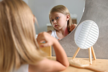 Suffering from allergy. Little girl looking at her neck in mirror indoors