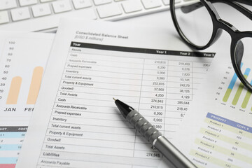Fototapeta premium Accounting documents, pen, glasses and computer keyboard on white table, closeup
