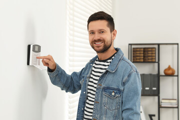 Man entering code on home security system indoors