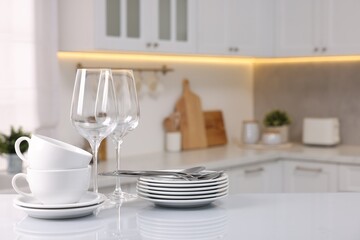 Set of clean dishware, glasses and cutlery on table in kitchen, space for text