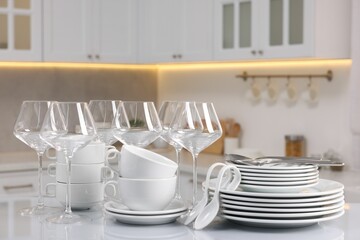 Set of clean dishware, glasses and cutlery on table in kitchen