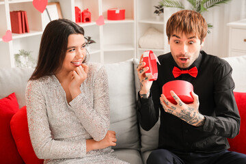 Young woman greeting her beloved boyfriend with Valentine's day at home
