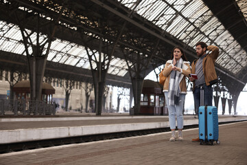 Being late. Worried couple with suitcase waiting at train station, space for text