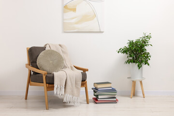 Stylish living room interior with comfortable armchair, blanket and houseplant