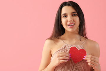 Beautiful young woman with red heart on pink background. Valentine's day celebration