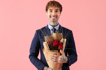 Handsome young man with bouquet of roses on pink background. Valentine's day celebration