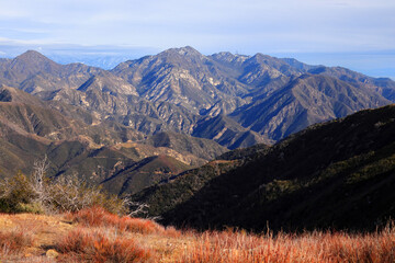 Mountain valley. Red dry grass and blue cloudy sky behind.
