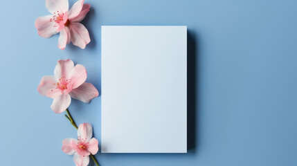 A clean white blank card surrounded by delicate pink cherry blossoms against a soothing blue background, perfect for spring greetings.