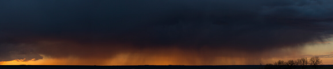 Landscape at sunset. A thunderstorm is approaching the village. Tragic gloomy sky. Panorama.