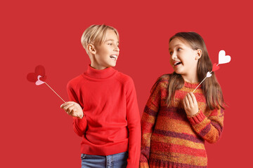 Happy little children with paper hearts on red background. Valentine's day celebration