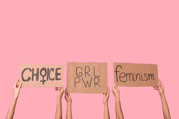Female hands holding cardboard pieces with text CHOICE, GRL PWR and FEMINISM on pink background