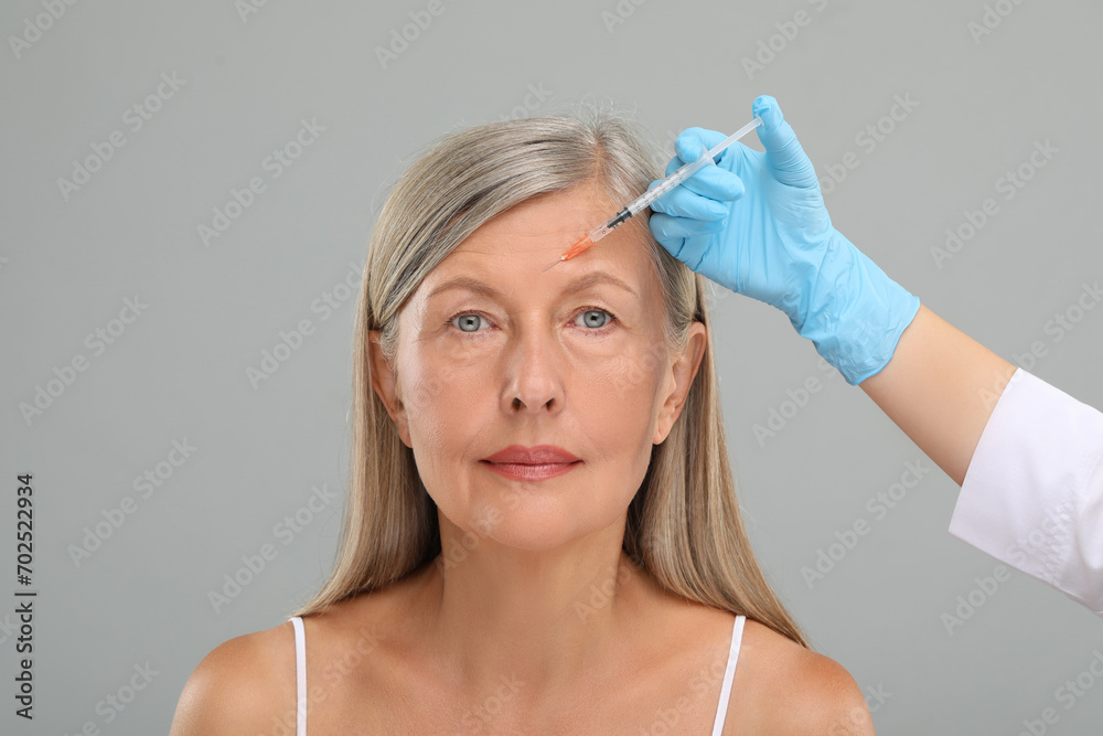 Sticker Doctor giving facial injection to senior woman on light grey background, closeup. Cosmetic surgery