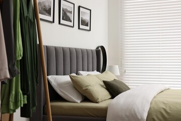 Window with horizontal blinds and comfortable bed in room