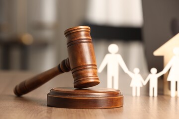 Law concept. Gavel and figures of parents with children on wooden table, closeup