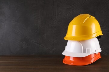 Hard hats on wooden table, space for text. Safety equipment