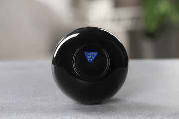 Magic eight ball with prediction Looks Like Yes on light gray table, closeup