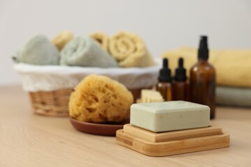 Soap bar, sponge and bottles of essential oils on light wooden table. Spa therapy