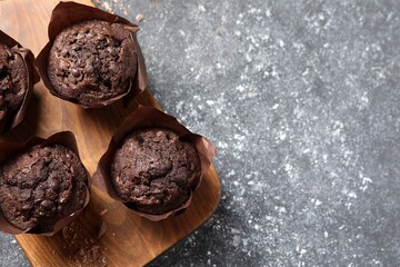Tasty chocolate muffins on grey table, top view. Space for text