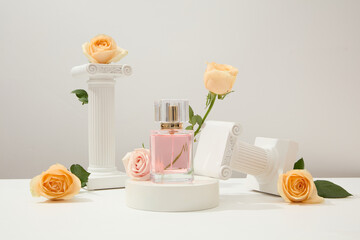 On a white background, a perfume bottle is displayed on a podium, surrounded by decorative pedestals and fresh roses. Cosmetic mockup for branding.