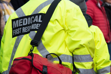 Close-up of a medical first responder wearing a bright fluorescent yellow coat with a grey...
