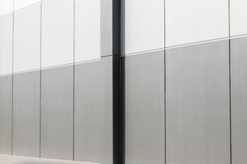 The exterior wall of a contemporary commercial style building with aluminum metal composite panels in various shapes. The futuristic building has engineered diagonal cladding steel frame panels. 