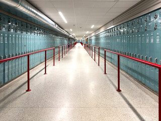A long hallway or tunnel at a university filled with green metal vertical combination lockers....