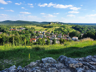 Fototapeta na wymiar From the top of the Hill, the panoramic view of a small town in the interior of Poland, with its houses amid green trees, grass and a beautiful blue sky, with some clouds.