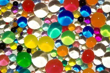 Abstract texture with multicolored transparent decorative gel balls. Hydrogel colorful round elements. Close up photo.