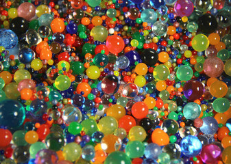 Abstract texture with multicolored transparent decorative gel balls. Hydrogel colorful round elements. Close up photo.