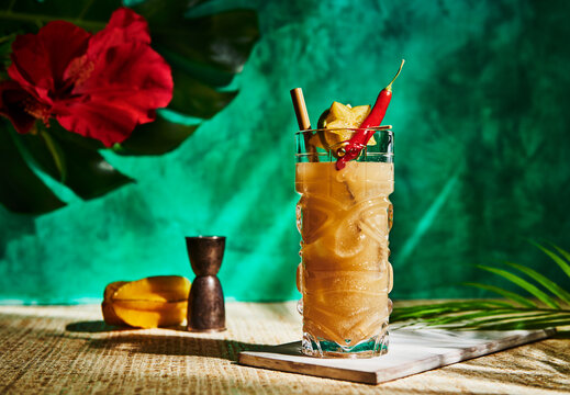 Tropical tiki cocktail with star fruit, lime, and a hot pepper garnish