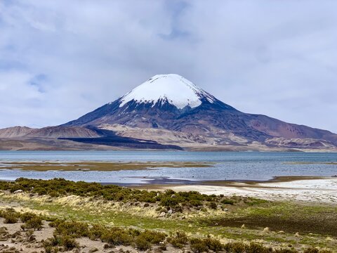 Parinacota dormant stratovolcano in Lauca national park on border of Chile and Bolivia. Snowcapped volcano with Rio Lauca, Lake Chungar&aacute; and Chilean altiplano in foreground. The Andes at altitude