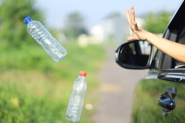 female driver's hand throwing plastic waste on the highway through the car window.  bad behavior...
