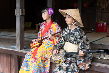 沖縄の民族衣装を着て三線を引く日本人の子ども