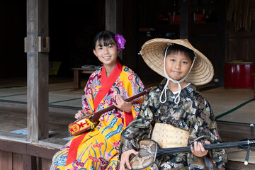 沖縄の民族衣装を着て三線を引く日本人の子ども