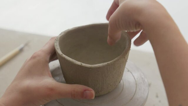 Skillfully molding a clay cup's surface with fingers, creating intricate texture in a charming studio