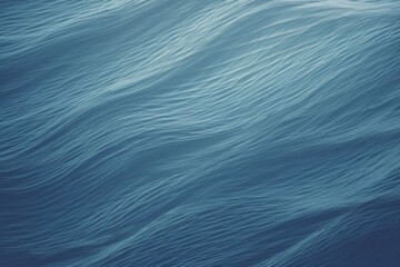 An abstract, close-up texture of ocean waves captured in a soothing blue hue, resembling brush strokes in a painting. The tranquil gradient and flowing patterns invoke the essence of calm sea waters