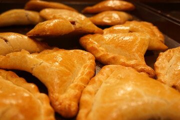 Arrow-shaped crackly pastries under yellowish light, in tray