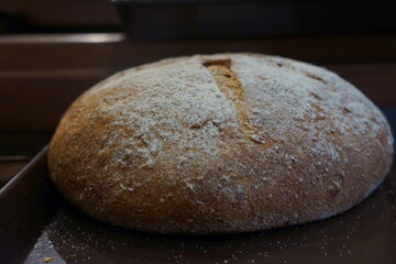Close up of big loaf of bread with cross on top, powdered with flour