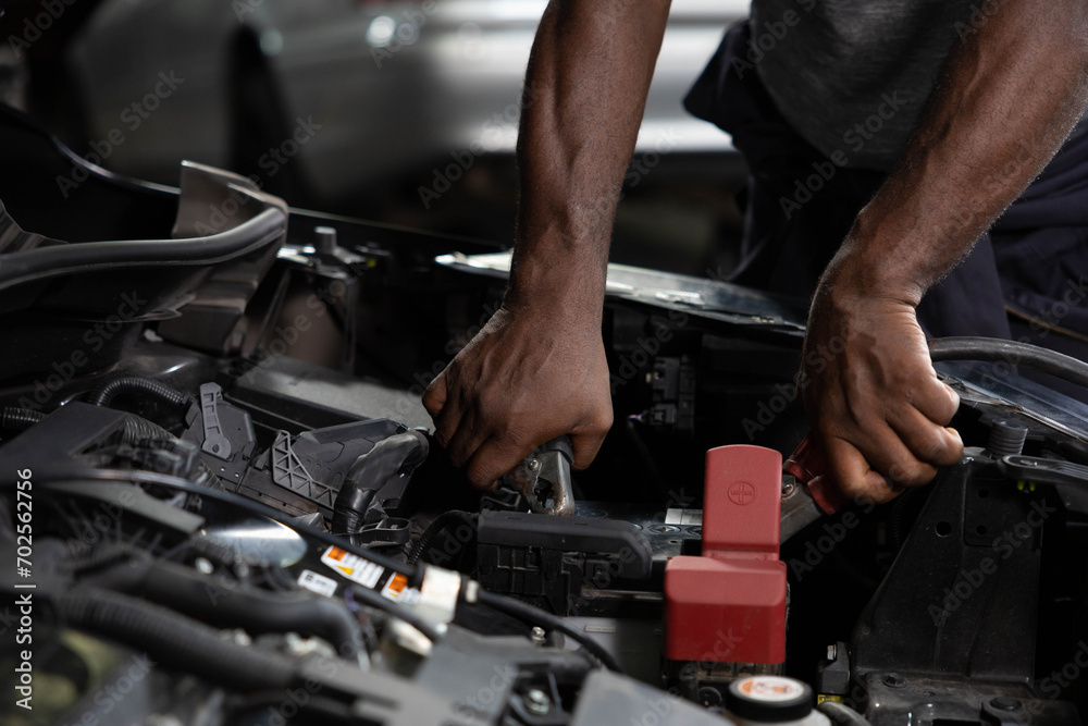 Wall mural close up mechanic worker hands holding battery cable for jumping battery of a car in automobile repa