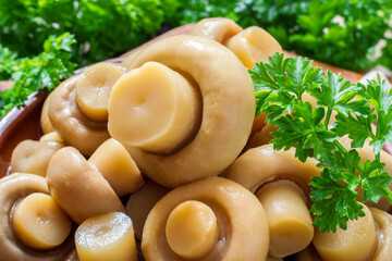 Marinated champignon mushrooms close-up. Canned mushrooms with fresh parsley.