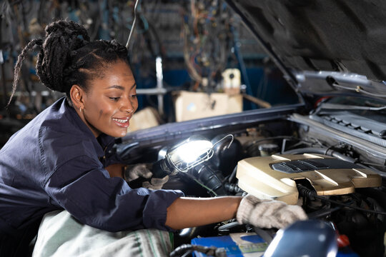 mechanic using flashlight for checking and fixing a car in automobile repair shop - Powered by Adobe