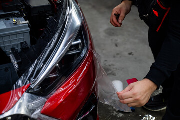 The process of applying protective vinyl film to car headlights in detailing. 