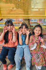 vertical photo of three smiling and happy latina girls in a park on a sunny day - friendship concept