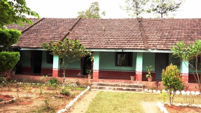 Government higher primary school building under red tiled roof and with walls painted with colorful images and texts of basic knowledge. 