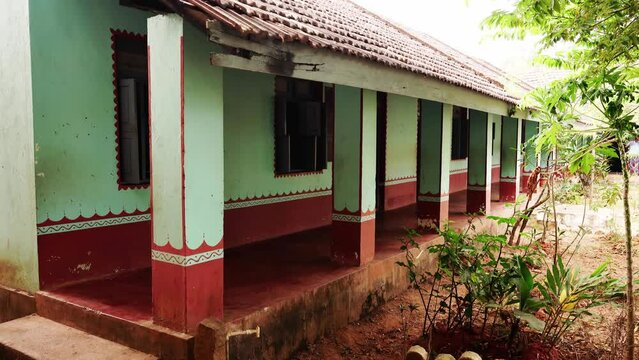 Government higher primary school building under red tiled roof and with walls painted with colorful images and texts of basic knowledge. 