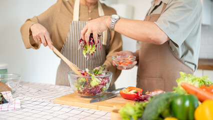 A lovely couple enjoying a healthy salad for their breakfast in the kitchen together.