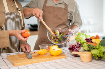 A lovely couple enjoying a healthy salad for their breakfast in the kitchen together.